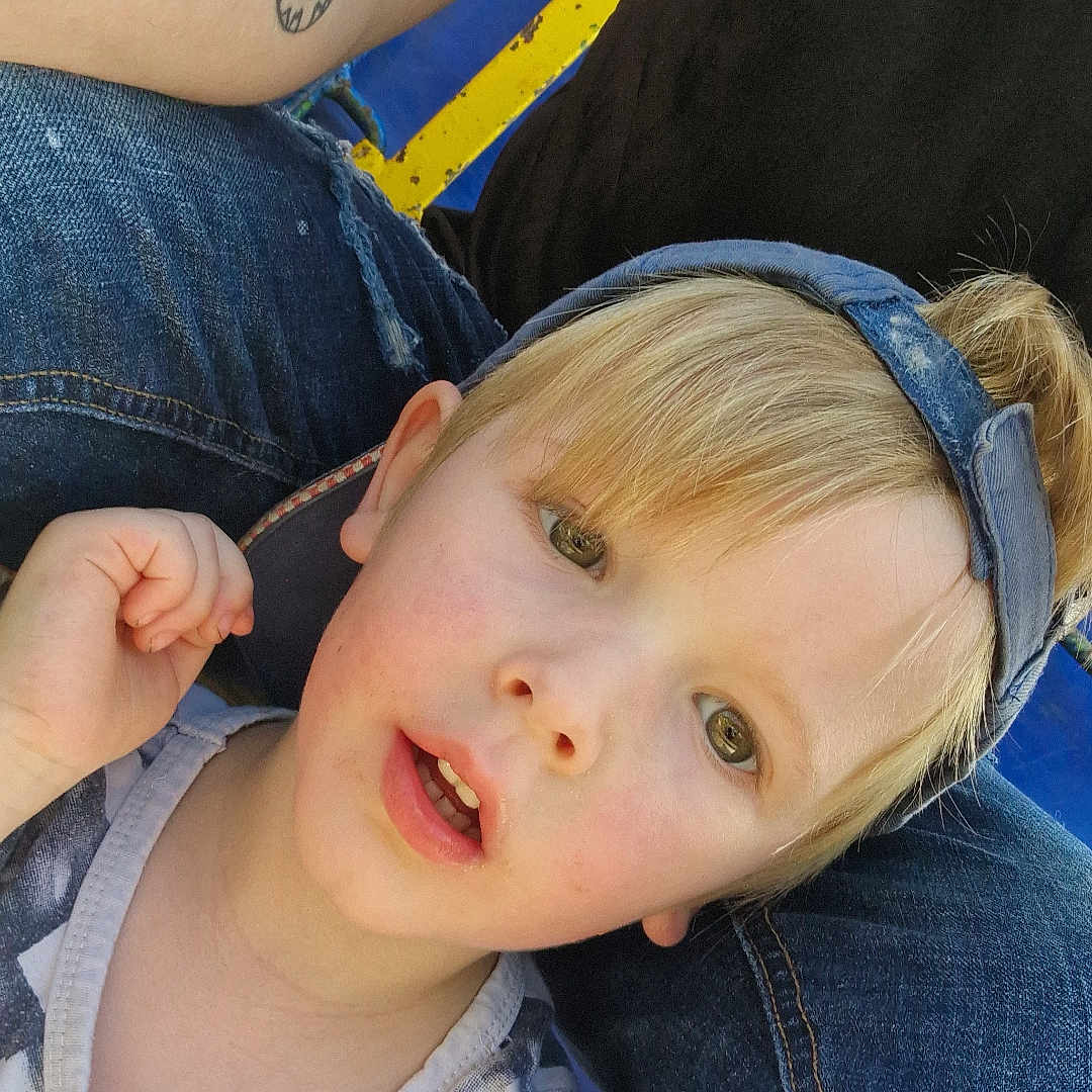 Cayden a rejoint le concours — aidez-le/la à gagner de superbes lots ! blonde_hair, casual, casual_clothing, child, closeup, curious_expression, daylight, denim_cap, face, headwear, human, jeans, light_skin, open_mouth, outdoor, person, portrait, sitting, tattoo, young_child