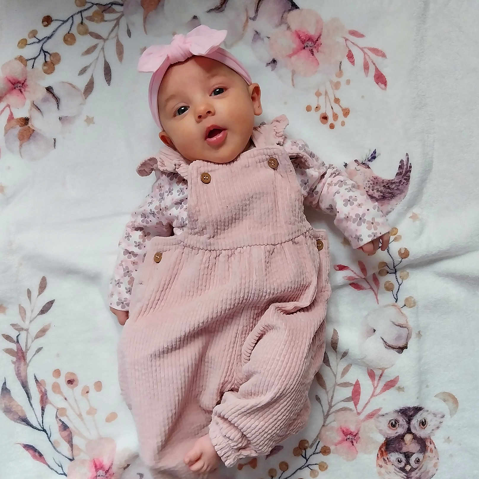 Elena a rejoint le concours — aidez-le/la à gagner de superbes lots ! baby, infant, pink_clothing, headband, floral_blanket, owl_illustration, soft_texture, cute, lying_down, pastel_colors, adorable, child, portrait, baby_girl, cozy, pattern, cute_expression, indoor, small_child, warm