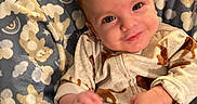 Carter is registered to the contest to win money with this photo: baby, baby_seat, blanket, blue, child, clothing, comfort, cozy, cute, expression, face, happy, indoors, infant, pattern, portrait, smiling, soft_texture, warm_light, young_child