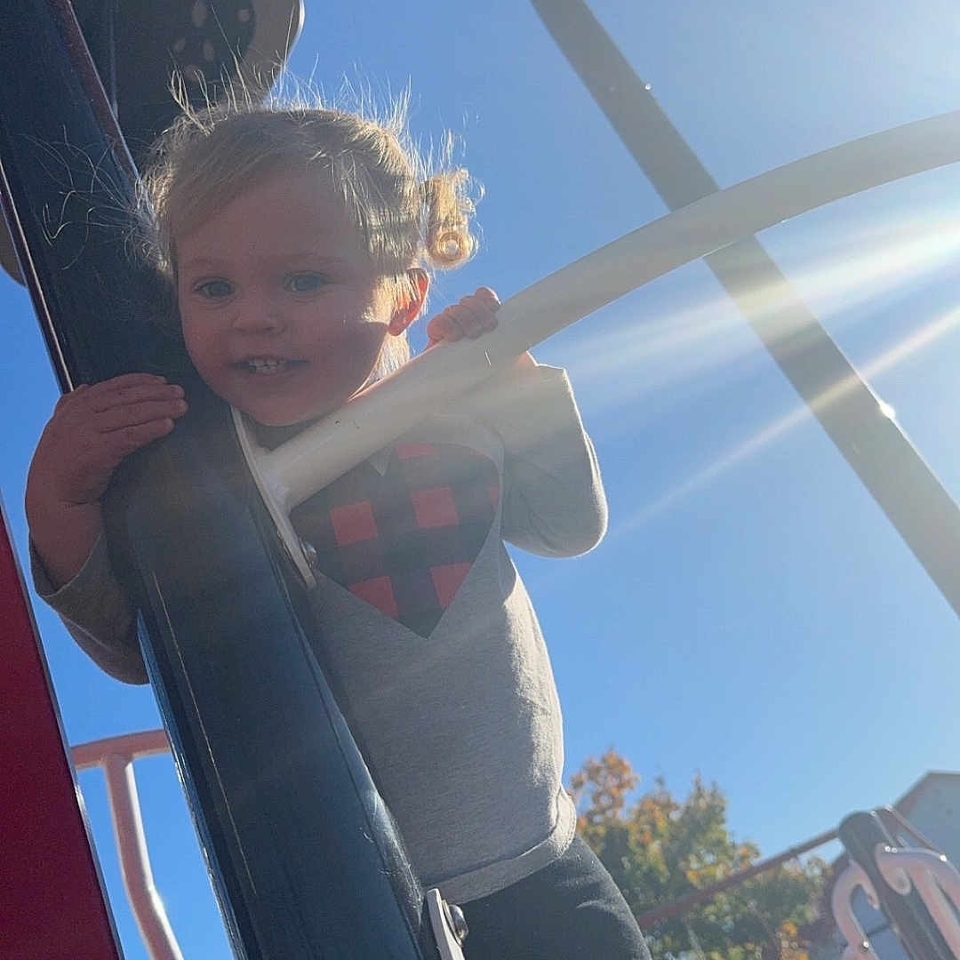 Jaelynn is registered to the contest to win money with this photo: architecture, baby, building, clothing, face, grass, head, nature, outdoorplayarea, outdoors, park, person, photography, plant, playarea, portrait, shelter, slide, t_shirt, toy