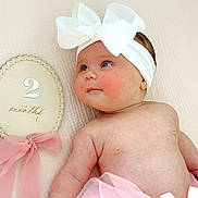 Charlotte is registered to the contest to win money with this photo: baby, infant, headband, bow, pink, skirt, rosy_cheeks, blue_eyes, plush, soft_texture, decorative_plaque, ribbon, cute, portrait, child, newborn, lying_down, skin, closeup, adorable