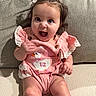 baby, baby_clothing, child, couch, dark_hair, dress, eyes, facial_expression, furniture, hair_bows, home, indoor, infant, lace, laughing, photography, pink_outfit, portrait, sitting, smiling