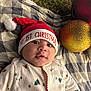 Kingston is registered to the contest to win money with this photo: baby, infant, christmas_hat, holiday, festive, blanket, grass, ornaments, red_hat, white_pom_pom, face, cute, celebration, outdoor, winter_clothing, smiling, holiday_season, child, christmas, portrait