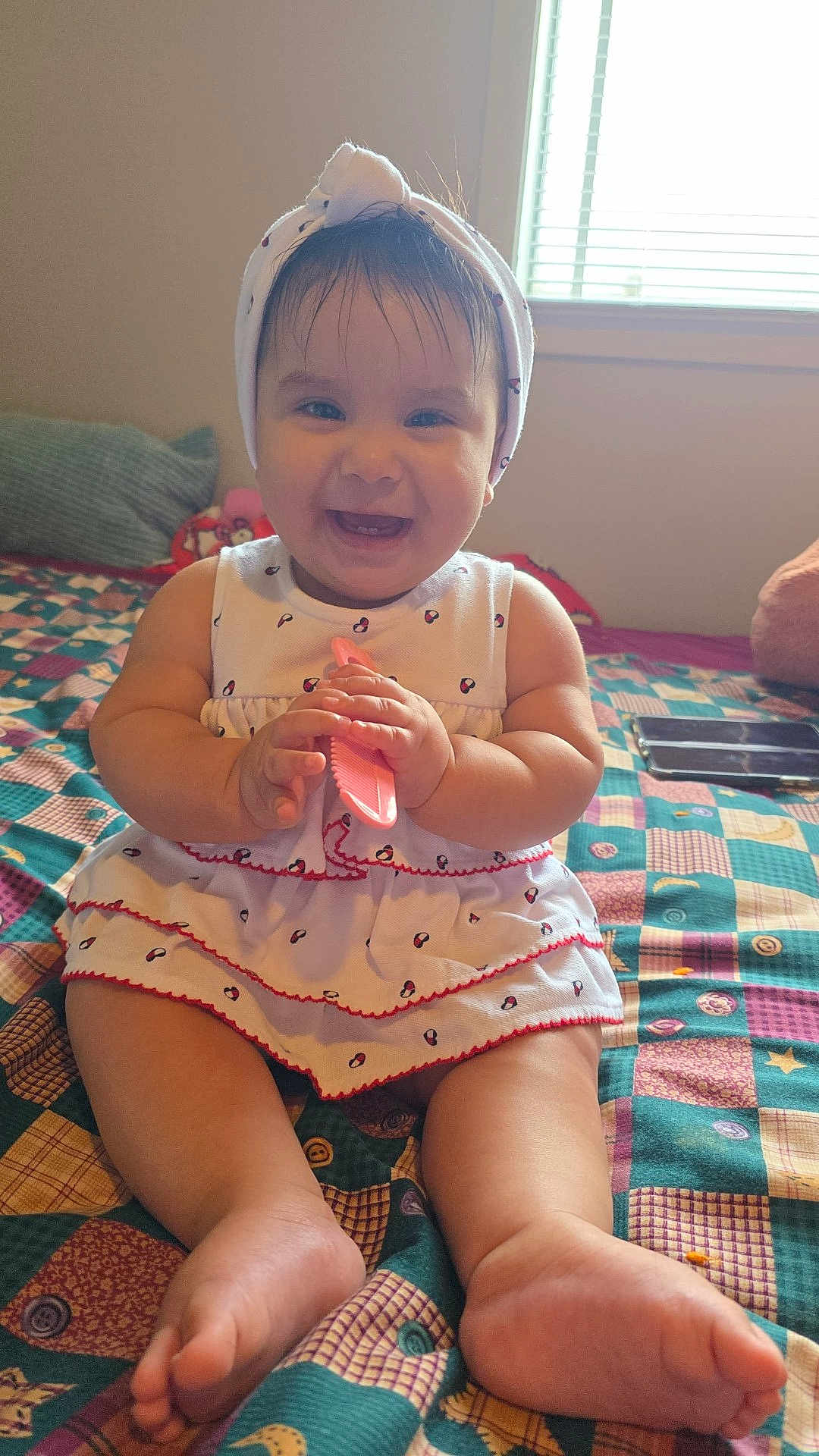 Shaira joined the competition — help win amazing prizes! baby, smiling, headband, white_dress, sitting, bed, quilt, colorful, indoor, child, cute, happy, comb, toys, window, natural_light, skin, feet, hands, infant