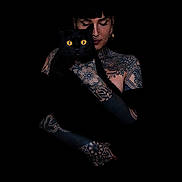 Oprah a rejoint le concours — aidez-le/la à gagner de superbes lots ! black_cat, tattoo, person, yellow_eyes, portrait, dark_background, face, hand, earring, nose_ring, tattooed_skin, black_fur, animal, pet, holding, close_up, mystical, contrast, studio_photo, expression
