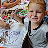 Ezekiel is registered to the contest to win money with this photo: child, children, smiling, crafting, art_project, markers, colored_paper, feathers, table, classroom, indoor, portrait, boy, girl, creative_activity, drawing, painting, art_supplies, seated, group_activity