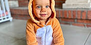 Charles a rejoint le concours — aidez-le/la à gagner de superbes lots ! toddler, child, onesie, hood, blue_eyes, smile, indoor, floor, tile, brick_wall, fireplace, crib, cute, cozy, baby, sitting, fuzzy_clothing, hands, portrait, young_child