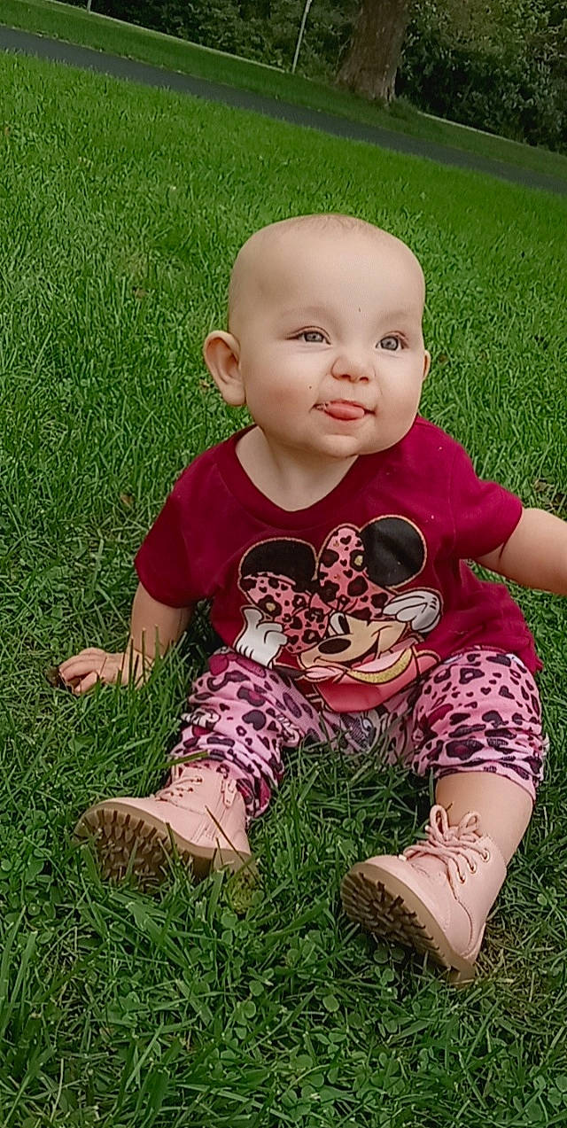 Evalyn is registered to the contest to win money with this photo: baby, baby_toddler_clothing, child, finger, fun, garden, grass, grassland, happy, lawn, meadow, pattern, people_in_nature, person, plant, sitting, skin, sleeve, smile, t_shirt