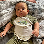 Legend is registered to the contest to win money with this photo: baby, infant, child, blanket, bed, clothing, crocodile_design, cute, face, head, lying_down, looking_up, person, portrait, shorts, soft_texture, toddler, young_child, indoor, skin