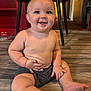 baby, child, smiling, sitting, floor, indoor, shorts, bare_chest, toy, table, legs, hands, face, happy, cute, skin, blue_eyes, furniture, home, expression