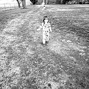 Atlasjimmy is registered to the contest to win money with this photo: child, walking, dirt_path, rural, trees, fence, boots, grass, outdoor, nature, black_and_white, person, field, overcast, vehicle, landscape, bare_trees, countryside, daytime, young