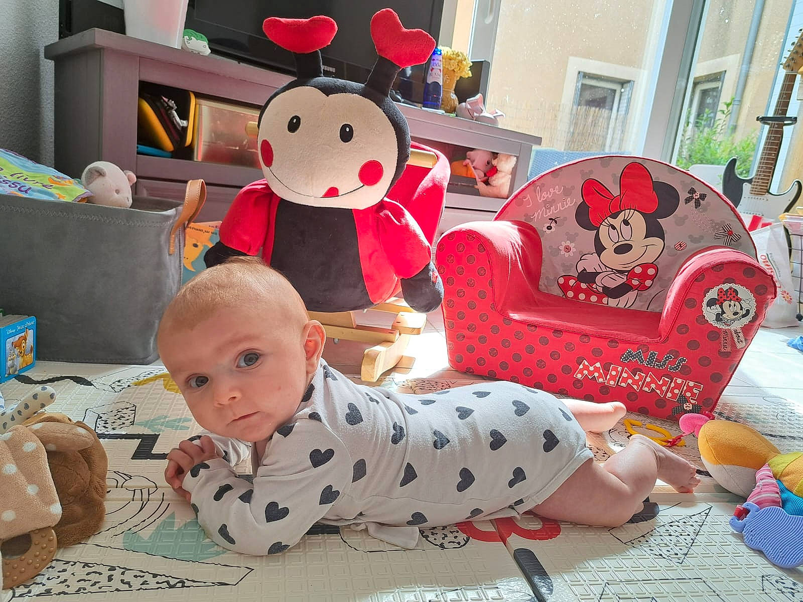 Maya a rejoint le concours — aidez-le/la à gagner de superbes lots ! baby, baby_toddler_clothing, child, comfort, couch, event, flooring, fun, happy, lap, living_room, pattern, people, person, product, room, sitting, stuffed_toy, textile, toddler