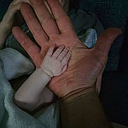 Saige joined the competition — help win amazing prizes! baby, hand, adult, person, skin, face, family, contrast, closeup, love, parent, child, protection, touch, warmth, skin_texture, blanket, indoor, portrait, intimacy