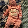 baby, bed, blanket, child, clothing, cute, face, indoors, infant, lying_down, mittens, newborn, pattern, person, pink, quilt, sleepwear, soft_lighting, striped, text_on_clothing
