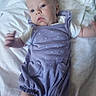 baby, infant, child, purple_clothing, polka_dot, romper, white_blanket, lying_down, indoor, person, young_child, face, head, arm_motion, cute, soft_texture, newborn, sleepwear, baby_girl, toddler