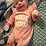 apparel, baby, blanket, child, cozy, cute, face, indoors, infant, lying_down, mittens, newborn, onesie, person, pink, portrait, quilt, sleepwear, soft_texture, striped_clothing