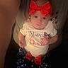 adult, arms, baby, blue_skirt, bows, celebration, child, clothing, cute, eyes, face, festive, headband, indoor, infant, person, portrait, red_bow, stars, white_shirt