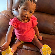 Elyse joined the competition — help win amazing prizes! braided_hair, casual_clothing, child, comfortable, curious, cute, furniture, head_tilt, indoor, leather_couch, looking_at_camera, person, pink_shirt, portrait, sitting, small_child, toddler, white_bow, yellow_shoes, young_child