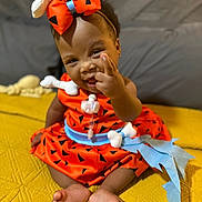 Elyse joined the competition — help win amazing prizes! baby, child, smile, orange_dress, headband, bow, sitting, yellow_blanket, indoor, cute, happy, person, foot, hand, portrait, infant, clothing, playful, expression, fun