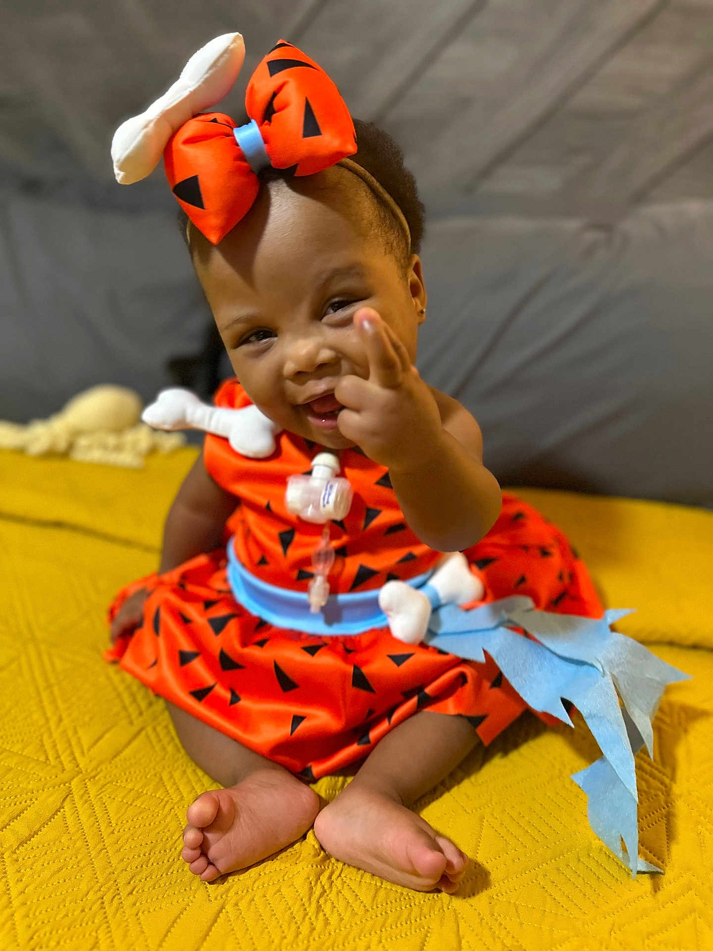 Elyse joined the competition — help win amazing prizes! baby, child, smile, orange_dress, headband, bow, sitting, yellow_blanket, indoor, cute, happy, person, foot, hand, portrait, infant, clothing, playful, expression, fun