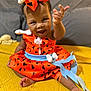 Elyse is registered to the contest to win money with this photo: black, blanket, bow, child, clothing, costume, cute, face, feet, hand, happy, headband, indoor, orange, person, playful, sitting, smile, toddler, yellow