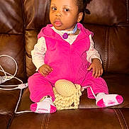 Elyse joined the competition — help win amazing prizes! brown_background, charging_cable, child, crochet_toy, cute, earring, feet, flash_lighting, hair_buns, hands, home, leather_couch, living_room, medical_tube, pink_outfit, plush_toy, portrait, sitting, socks, toddler