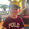 child, boy, smile, hat, pikachu, indoors, shirt, maroon, polo, face, plant, window, light, furniture, chair, carpet, portrait, happy, casual, home