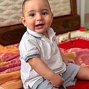 Isaac a rejoint le concours — aidez-le/la à gagner de superbes lots ! baby, blanket, bright, carpet, casual_clothing, child, cute, face, furniture, happy, home, indoor, person, polo_shirt, portrait, sitting, smiling, striped_shorts, teeth, young_child