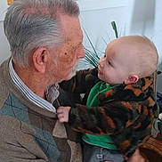Atticus joined the competition — help win amazing prizes! baby, cozy, elderly_man, face, gaze, grandparent, hands, holding, home, indoor, interaction, kitchen, love, patterned_jacket, person, plant, portrait, smile, sweater, vase