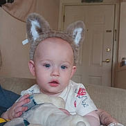 Atticus joined the competition — help win amazing prizes! baby, child, animal_ears, plush_toy, bottle, indoor, couch, clothing, door, wall_art, person, headwear, comfort, home, furniture, sitting, cute, young_child, infant, relaxed