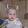 baby, child, animal_ears, plush_toy, bottle, indoor, couch, clothing, door, wall_art, person, headwear, comfort, home, furniture, sitting, cute, young_child, infant, relaxed
