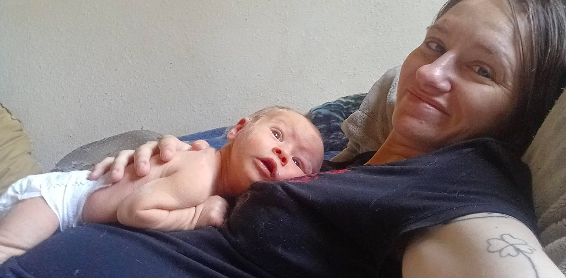 Atticus joined the competition — help win amazing prizes! adult, baby, blanket, bonding, casual, comfort, couch, diaper, expression, face, family, hand, head, indoor, person, relaxation, resting, skin, smile, tattoo