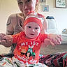 Atticus is registered to the contest to win money with this photo: baby, woman, child, indoor, tattoos, smile, clothing, easter, hat, pants, holding_hands, person, portrait, home, couch, decor, happy, family, cute, colorful