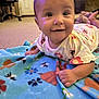 baby, blanket, carpet, child, clothing, colorful, cute, earrings, floor, floral_pattern, furniture, hand, happy, head, indoor, person, portrait, skin, smiling, toddler
