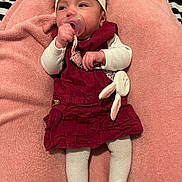 Aëla participe au concours pour gagner de l'argent avec cette photo : child, baby, infant, pacifier, headband, bow, blanket, pink_blanket, dress, maroon_dress, white_sleeves, tights, plush_toy, bunny, hand, face, portrait, lying_down, bedding, cozy