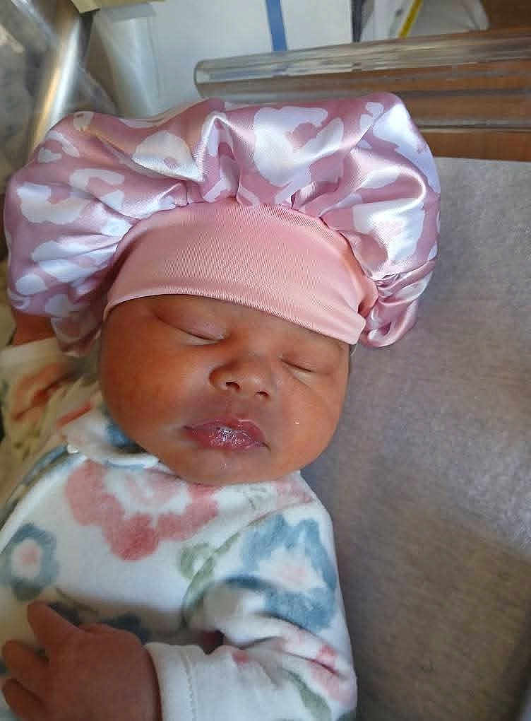 Zoē joined the competition — help win amazing prizes! baby, sleeping, infant, pink_bonnet, pajamas, floral_pattern, soft_fabric, close_up, face, peaceful, cute, resting, newborn, child, headwear, person, indoors, skin, hand, cozy