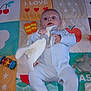 Archie joined the competition — help win amazing prizes! baby, infant, onesie, plush_toy, play_mat, toy, child, cute, lying_down, colorful, patterned, soft_toy, expression, indoors, person, young_child, hands, face, blue_clothing, comfort