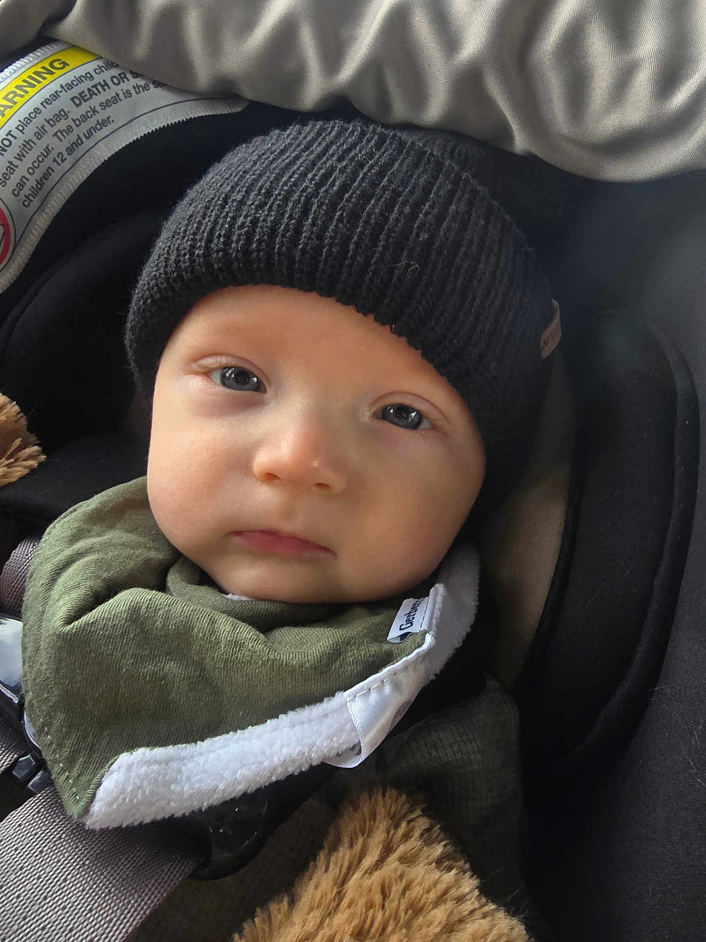 Weston is registered to the contest to win money with this photo: baby, infant, child, car_seat, beanie, hat, bib, face, eyes, cheeks, closeup, portrait, seatbelt, buckle, blanket, fur, cozy, warm, expression, clothing