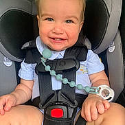 Adam is registered to the contest to win money with this photo: baby, car_seat, child, smiling, pacifier, safety_harness, cute, infant, happy, blue_shirt, seatbelt, closeup, indoors, sitting, toddler, child_safety, human, face, hands, legs