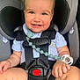 baby, car_seat, child, smiling, pacifier, safety_harness, cute, infant, happy, blue_shirt, seatbelt, closeup, indoors, sitting, toddler, child_safety, human, face, hands, legs