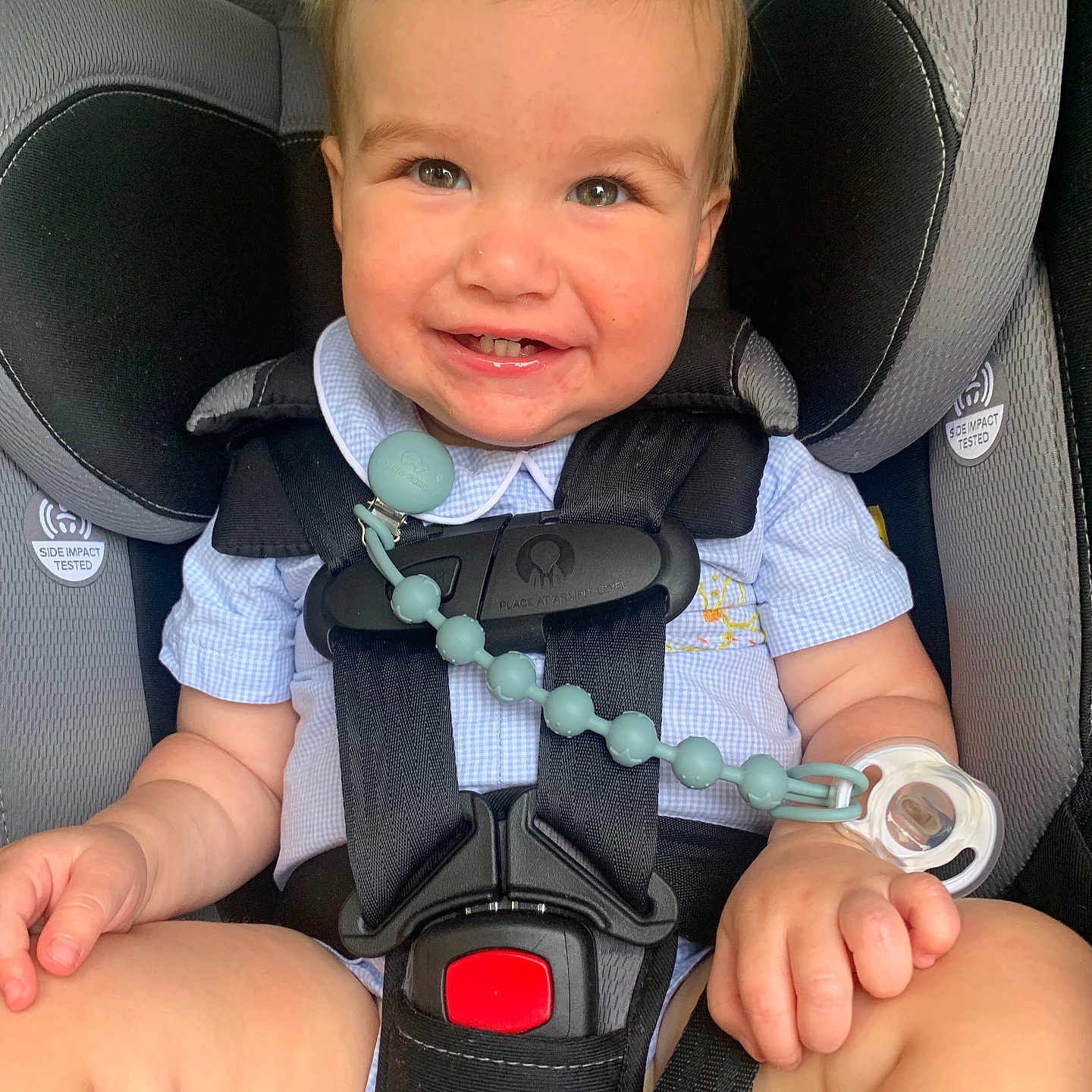 Adam is registered to the contest to win money with this photo: baby, blue_shirt, car_seat, child, child_safety, closeup, cute, face, hands, happy, human, indoors, infant, legs, pacifier, safety_harness, seatbelt, sitting, smiling, toddler
