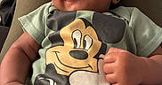 Nekoda joined the competition — help win amazing prizes! baby, car_seat, cartoon, child, close_up, clothing, curly_hair, face, green_shirt, hands, happy, indoor, infant, mickey_mouse, passenger, photography, portrait, seated, smiling, vehicle