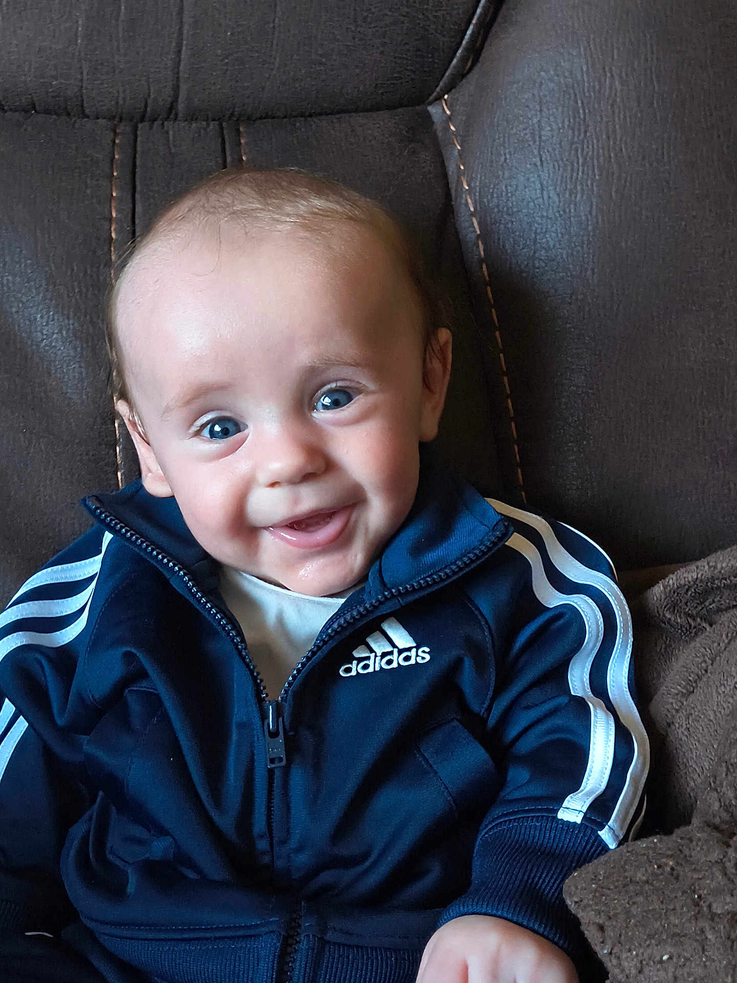 Ryan joined the competition — help win amazing prizes! baby, child, smiling, blue_eyes, adidas_jacket, sportswear, leather_chair, cozy, portrait, happy, cute, indoor, seated, clothing, young_child, person, face, jacket, zipper, casual