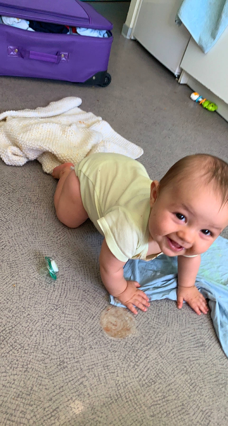 Kenzo participe au concours pour gagner de l'argent avec cette photo : baby, baby_toddler_clothing, backpack, blue, cheek, child, finger, floor, flooring, foot, green, happy, hardwood, joint, person, skin, smile, thumb, toddler, white
