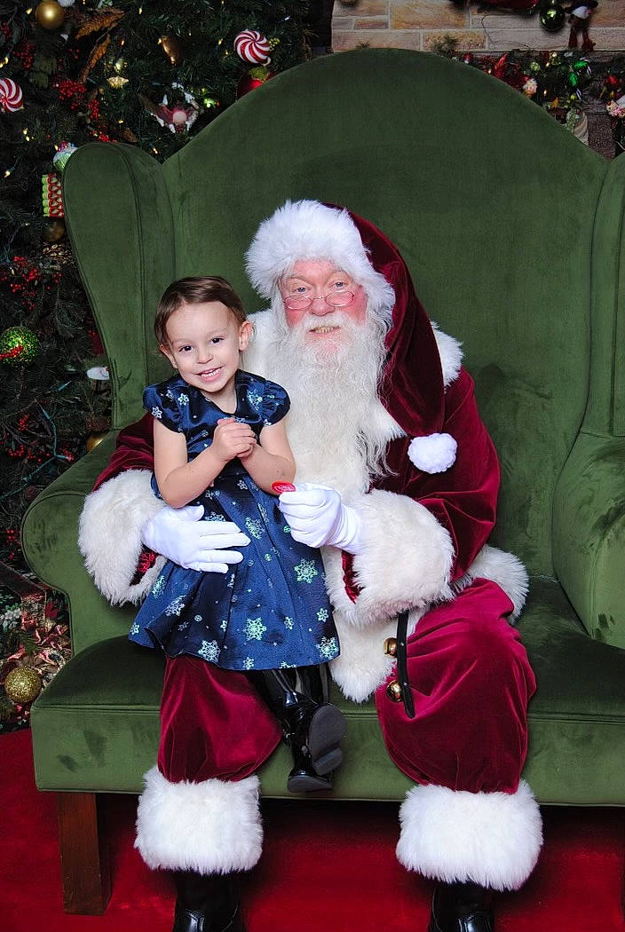 Emma is registered to the contest to win money with this photo: beard, christmas, christmas_decoration, christmas_tree, event, fictional_character, fun, green, happy, hat, head, headwear, holiday, human_body, joy, lap, person, photograph, red, santa_claus