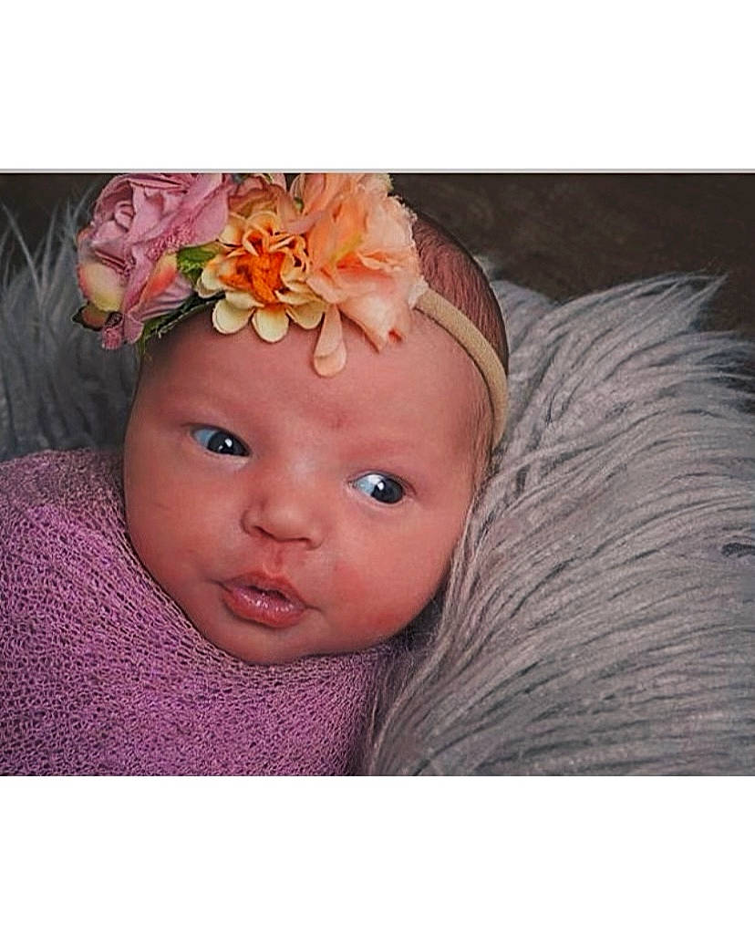 Delanie joined the competition — help win amazing prizes! baby, baby_toddler_clothing, brown_hair, dress, eye, eyelash, fashion_accessory, flower, hair_accessory, happy, head, headband, headgear, headpiece, headwear, jewellery, magenta, peach, person, petal