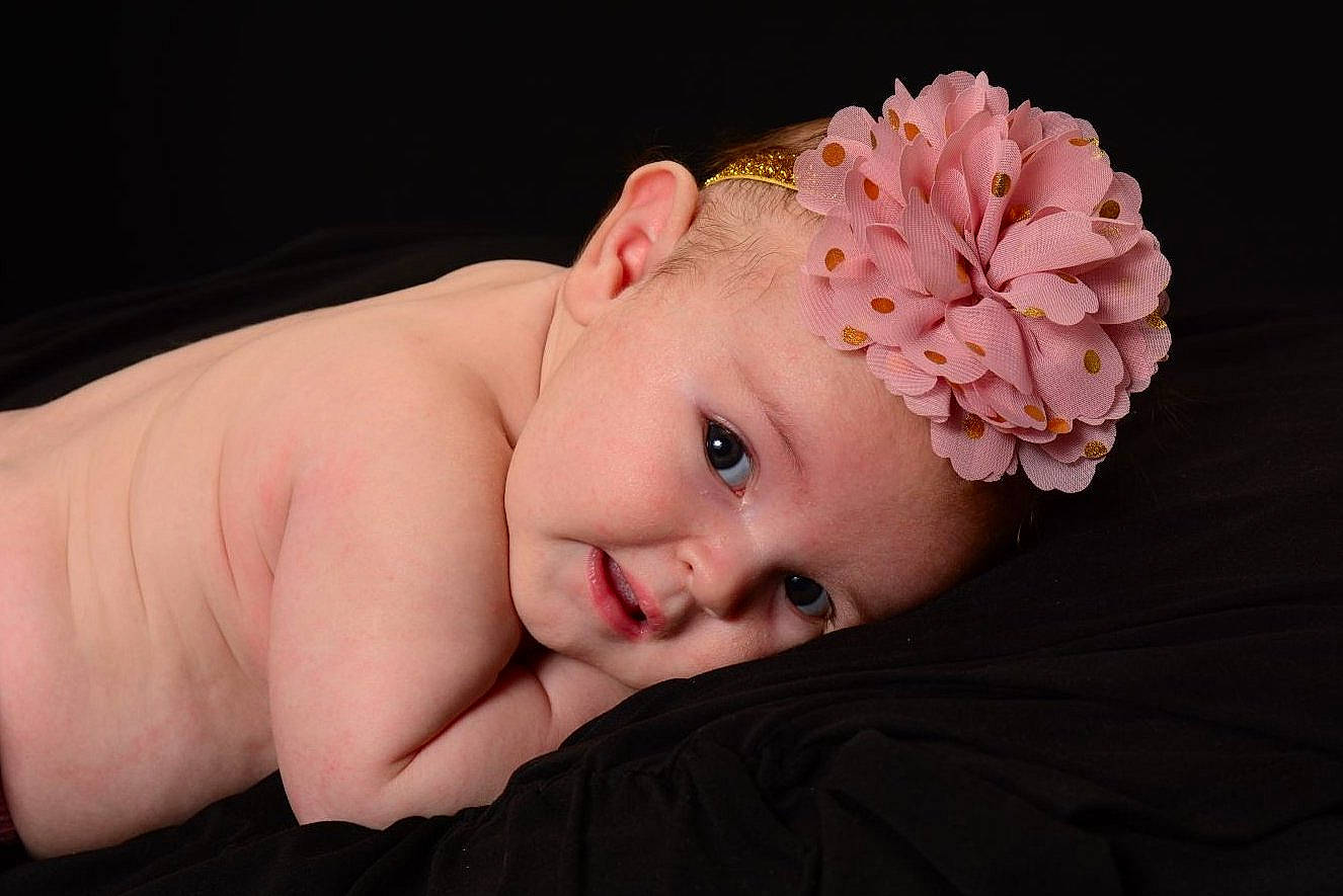 Lainey is registered to the contest to win money with this photo: baby, baby_toddler_clothing, cheek, chin, close_up, ear, eyebrow, eyelash, flash_photography, flower, headband, headpiece, jewellery, lip, neck, person, petal, pink, skin, smile