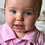 baby, child, face, blue_eyes, pink_shirt, teddy_bear_patch, close_up, portrait, cute, infant, young_child, collared_shirt, buttoned_shirt, indoor, soft_light, curious_expression, skin, head, person, smile