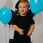 Kendrix is registered to the contest to win money with this photo: child, toddler, balloon, blue_balloon, black_balloon, white_balloon, smiling, happy, standing, shorts, tshirt, indoor, party, celebration, cute, young_child, hair, holding, person, studio