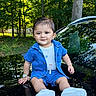 toddler, child, baby, portrait, sitting, outdoor, forest, trees, car, vehicle, blue_clothing, denim, shorts, shoes, watch, smiling, face, reflection, daylight, nature